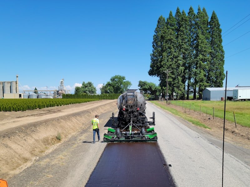 Asphalt Toronto crew member beside a paving machine during hot-mix placement